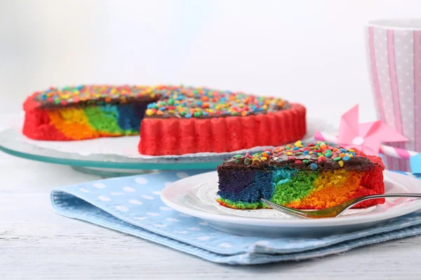 Heerlijke regenboogcake op plaat, op tafel, op lichte achtergrond — Stockfoto