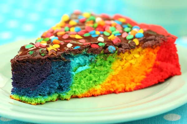 Délicieux gâteau arc-en-ciel sur assiette, sur fond de nappe — Photo