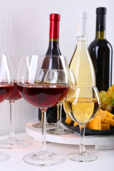 Botellas y vasos de vino, queso y uvas maduras en la mesa en la habitación — Foto de Stock
