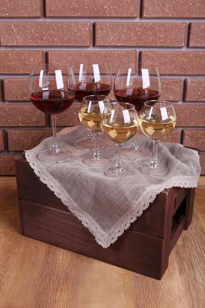 Glasses of wine on box on brick wall background — Stock Photo, Image