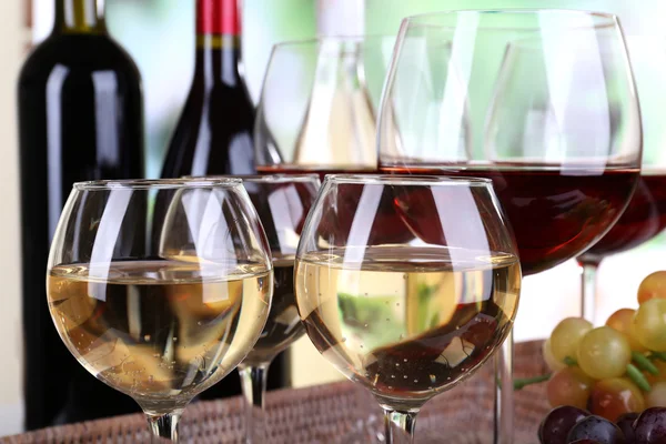 Bottles and glasses of wine and ripe grapes on table on natural background — Stock Photo, Image