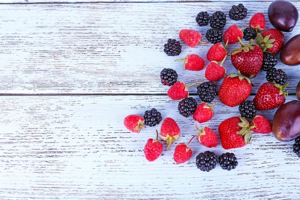 Different berries and plums on wooden table close-up — Stock Photo, Image