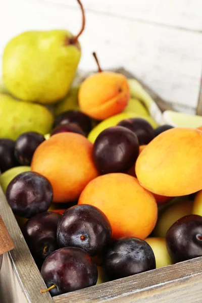 Frutas maduras en cajón sobre fondo de madera —  Fotos de Stock