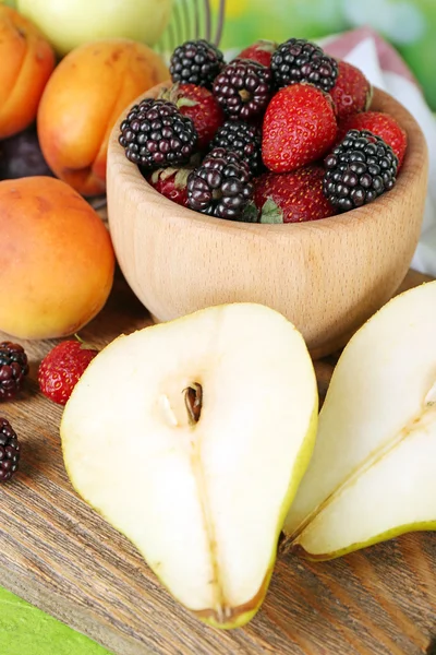 Rijp fruit en bessen in kom op tafel close-up — Stockfoto