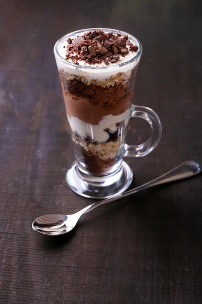 Iogurte, com creme de chocolate, chocolate picado e muesli servido em vidro sobre fundo de madeira — Fotografia de Stock