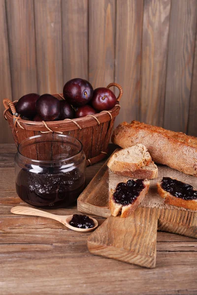 Pan con mermelada de ciruela y ciruelas en la mesa de madera de cerca —  Fotos de Stock