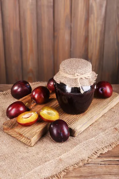 Engarrafamento de ameixa saboroso em jarro e ameixas na mesa de madeira close-up — Fotografia de Stock