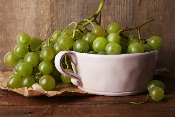 Uvas verdes em tigela sobre fundo de madeira — Fotografia de Stock