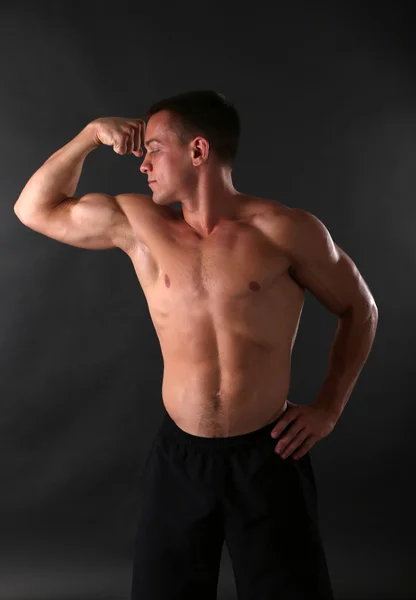 Schöner muskulöser junger Mann auf dunklem Hintergrund — Stockfoto