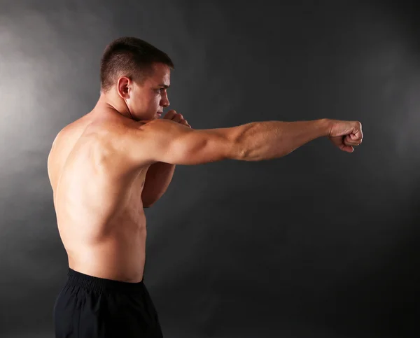 Handsome young muscular sportsman boxing on dark background — Stock Photo, Image