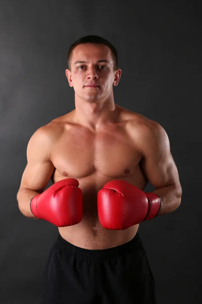 Guapo joven deportista muscular con guantes de boxeo sobre fondo oscuro —  Fotos de Stock