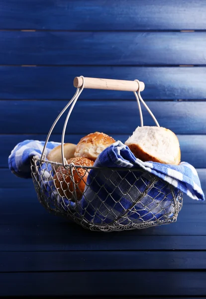 Tasty buns with sesame in wicker basket, on color wooden background — Stock Photo, Image