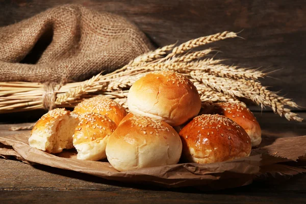 Tasty buns with sesame on wooden background — Stock Photo, Image