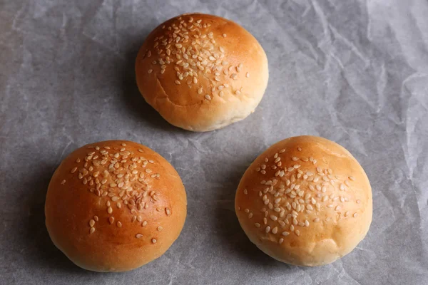 Leckere Semmeln mit Sesam auf Backblech, auf Holzboden — Stockfoto