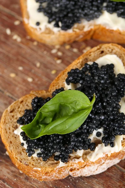 Tereyağı ve ahşap arka plan üzerinde siyah havyar ile ekmek dilimleri — Stok fotoğraf