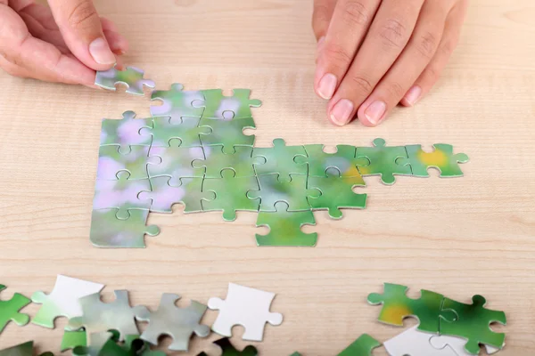 Hand met raadselstuk op houten tafel achtergrond — Stockfoto