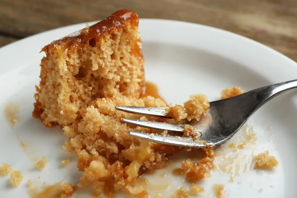 Половина їли смачний торт на тарілці на дерев'яному столі — стокове фото