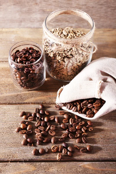 Kaffeebohnen in Stoffbeutel und Glasgefäßen auf Holzgrund — Stockfoto