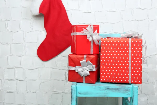 Kerstcadeautjes op blauwe stoel op bakstenen muur achtergrond — Stockfoto