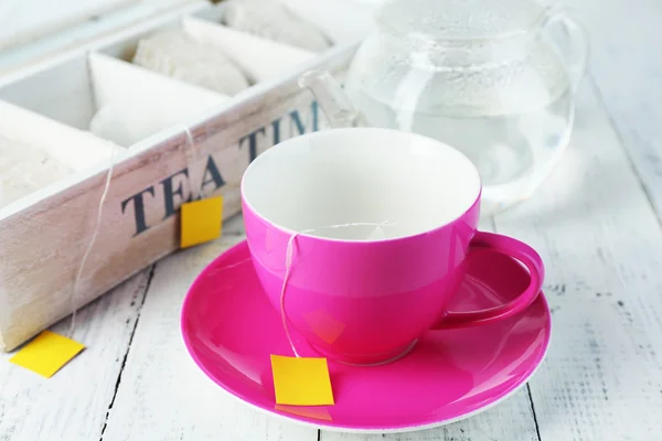 Puchar i czajnik z torebki herbaty na drewniany stół szczegół — Zdjęcie stockowe