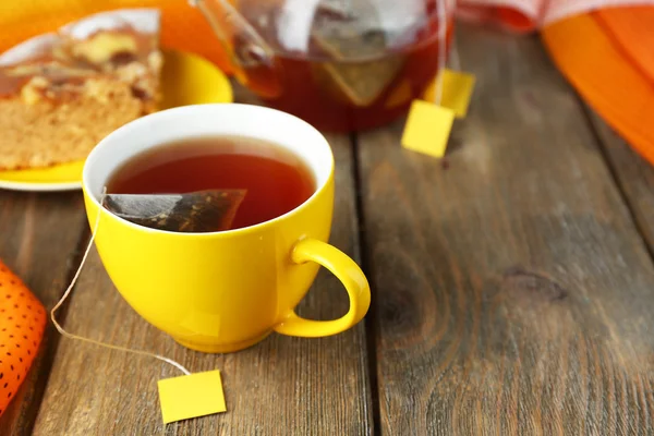 Copo com chá, bule e sacos de chá em mesa de madeira close-up — Fotografia de Stock