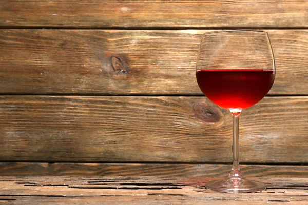 Copa de vino tinto sobre mesa de madera sobre fondo de pared de madera — Foto de Stock