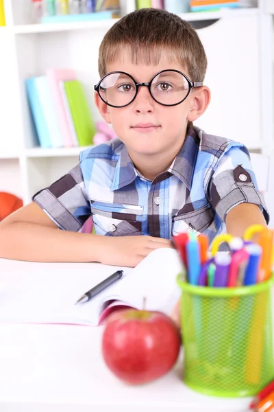 Skolpojke sitter vid bord — Stockfoto