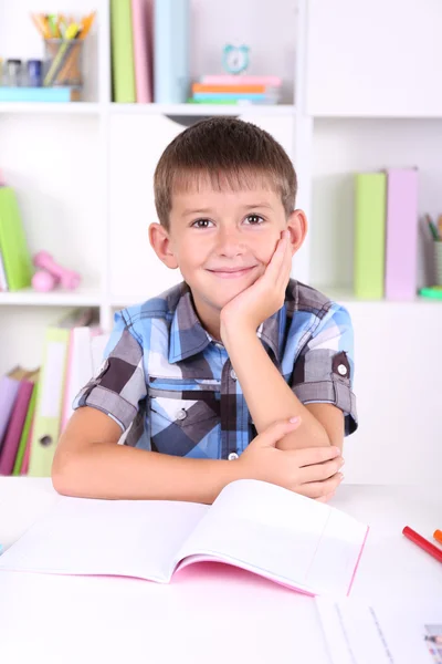 Skolpojke sitter vid bord — Stockfoto