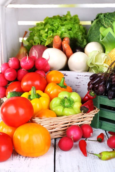 Vegetables in crate and in basket on white wooden box background — Stock Photo, Image