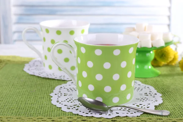 Two cups with sugar and wildflowers on napkin on table on light background — Stock Photo, Image