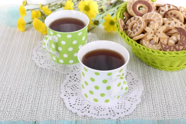 Two polka dot cups of tea with biscuits on fabric background — Stock Photo, Image