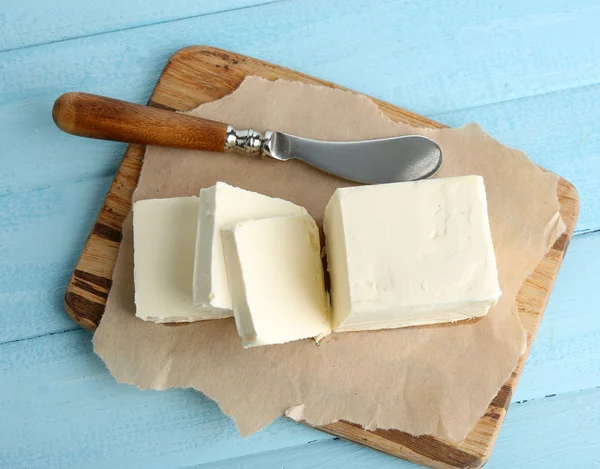 Mantequilla fresca en la tabla de cortar, sobre fondo de madera de color — Foto de Stock