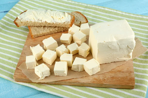 Fresh butter on cutting board and homemade bread, on color wooden background — Stock Photo, Image