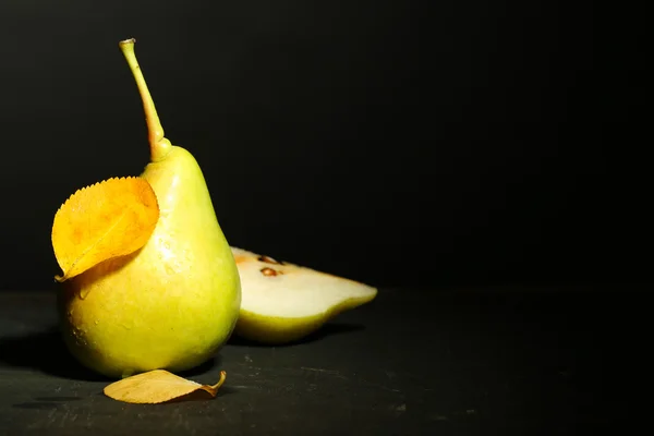 Rijpe smakelijke peer op houten tafel, op donkere achtergrond — Stockfoto