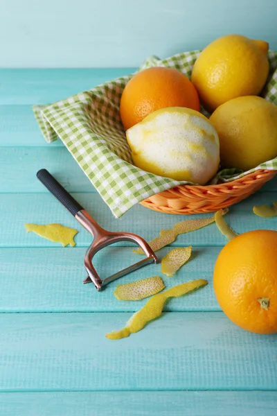 Citroenen en de sinaasappelen op servet in mand en Schilmes op blauwe houten achtergrond — Stockfoto