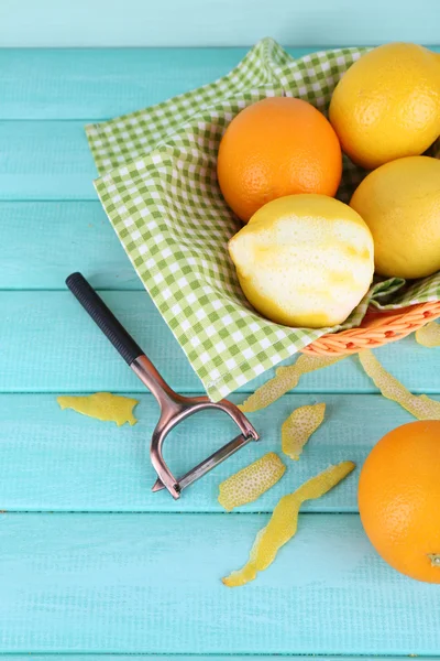 Lemons and oranges on napkin in basket and peeling knife on blue wooden background — Stock Photo, Image