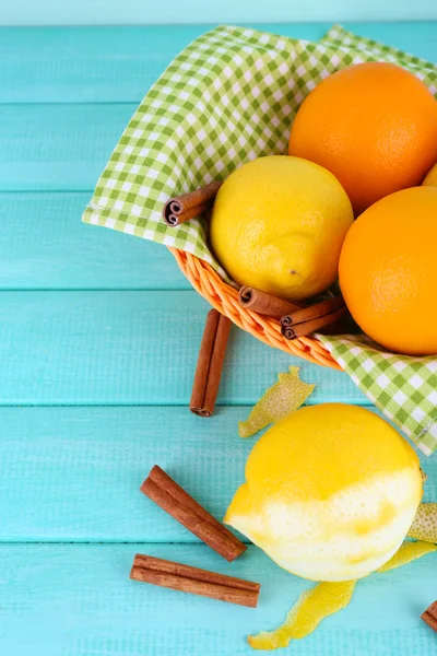 Lemons and oranges on napkin in basket and peeling knife on blue wooden background — Stock Photo, Image