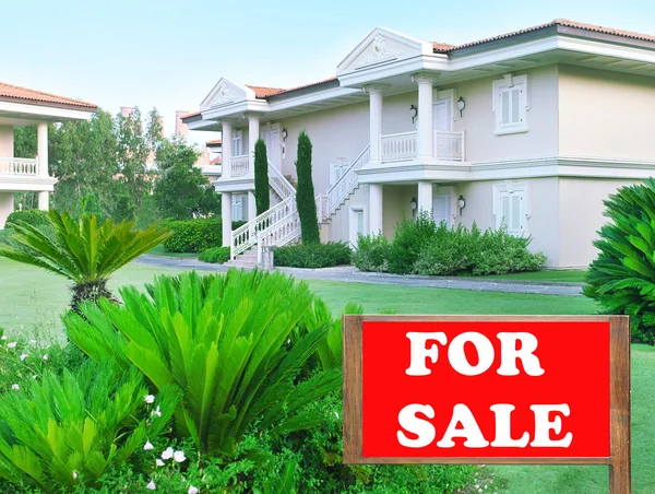 Real estate sign in front of new house for sale — Stock Photo, Image