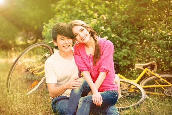 Jong koppel in park met fietsen zitten — Stockfoto