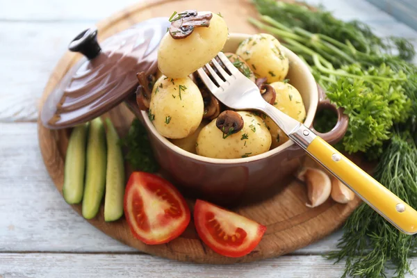 Unga kokt potatis i stekpanna med grönsaker på träbord, närbild — Stockfoto