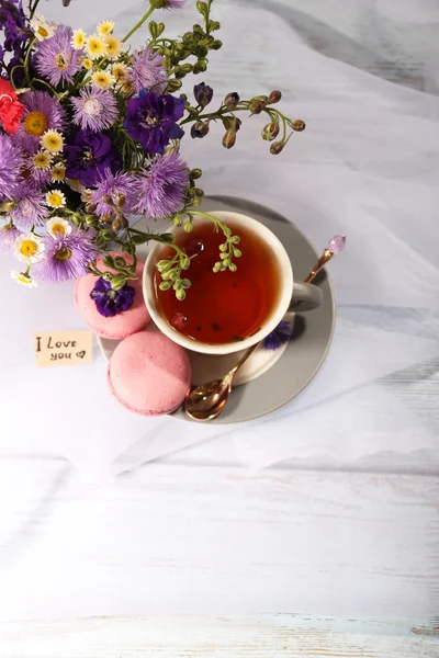 Cup of fresh herbal tea and beautiful bouquet of wildflowers on table — Stock Photo, Image