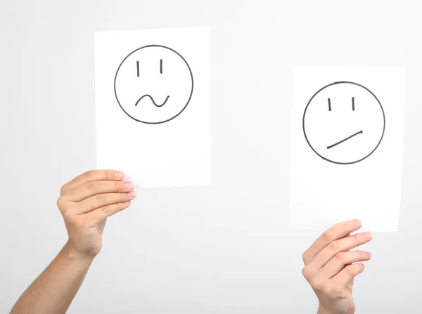 Mãos segurando diferentes smileys no fundo cinza — Fotografia de Stock