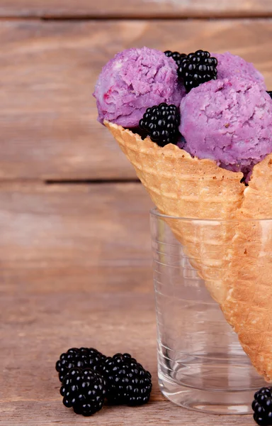 Вкусное мороженое с ягодами в вафельном конусе на коричневом деревянном фоне — стоковое фото