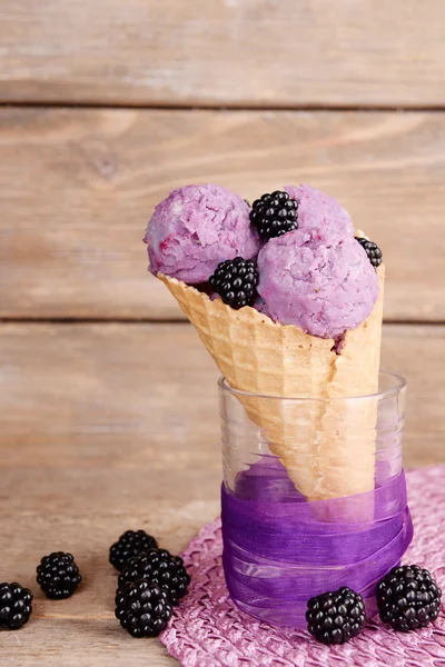 Вкусное мороженое с ягодами в вафельном конусе на коричневом деревянном фоне — стоковое фото