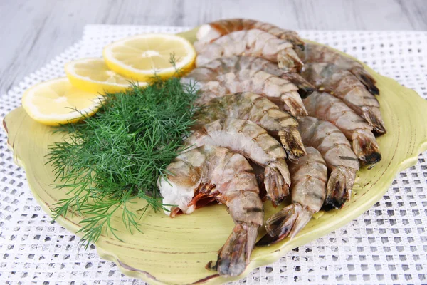 Square plate of prawns with dill and lemon on a yellow napkin on grey wooden background — Stock Photo, Image