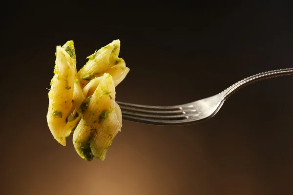 Pastas italianas sobre tenedor sobre fondo marrón oscuro — Foto de Stock