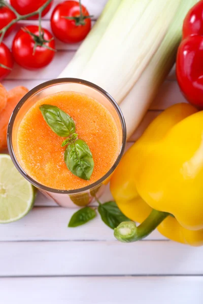 Glass of fresh carrot juice and vegetables on wooden background — Stock Photo, Image