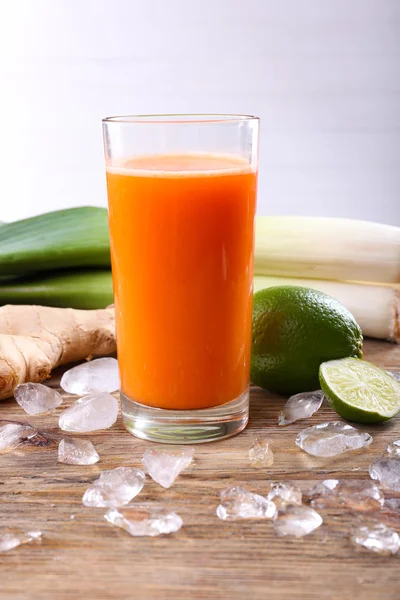 Glass of fresh carrot juice and vegetables on wooden table — Stock Photo, Image