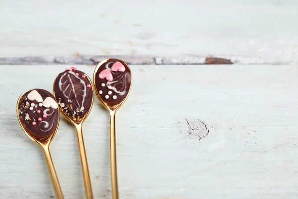 Spoons with tasty chocolate for party on old wooden table — Stock Photo, Image