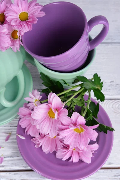 Kopjes en schotels met bloemen op houten achtergrond — Stockfoto